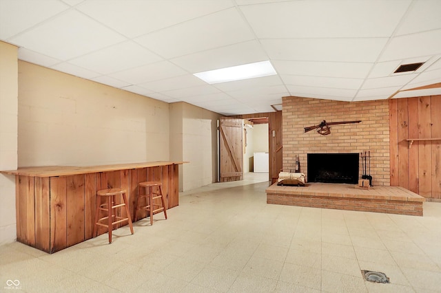 bar with light floors, a paneled ceiling, visible vents, wooden walls, and a bar