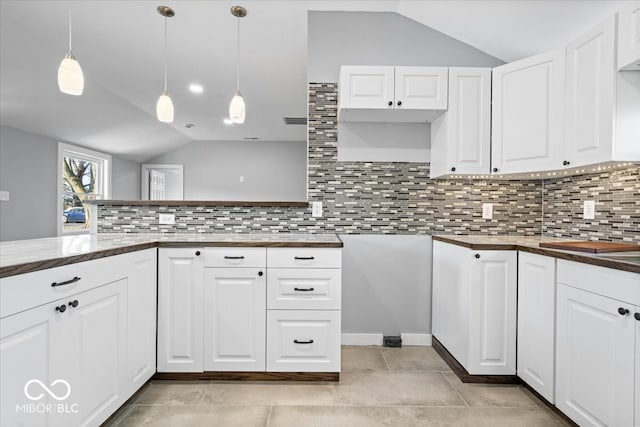 kitchen with white cabinetry, vaulted ceiling, and backsplash