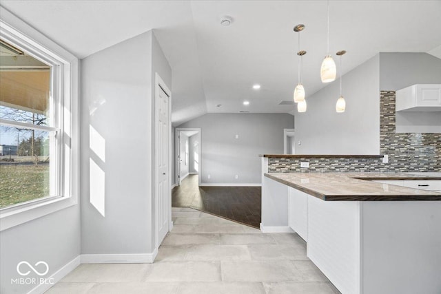 kitchen featuring decorative light fixtures, backsplash, white cabinets, and vaulted ceiling