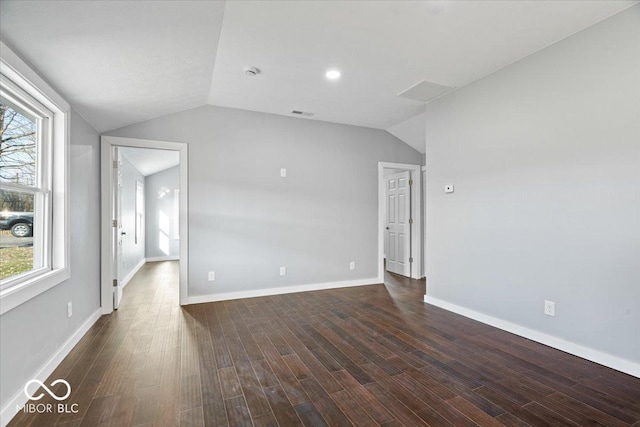 spare room with plenty of natural light, dark wood finished floors, and vaulted ceiling