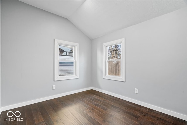 spare room featuring vaulted ceiling, baseboards, and dark wood-style flooring