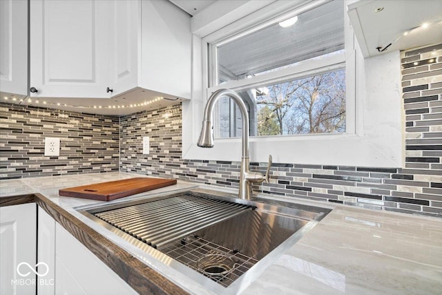 details featuring white cabinets, backsplash, and a sink