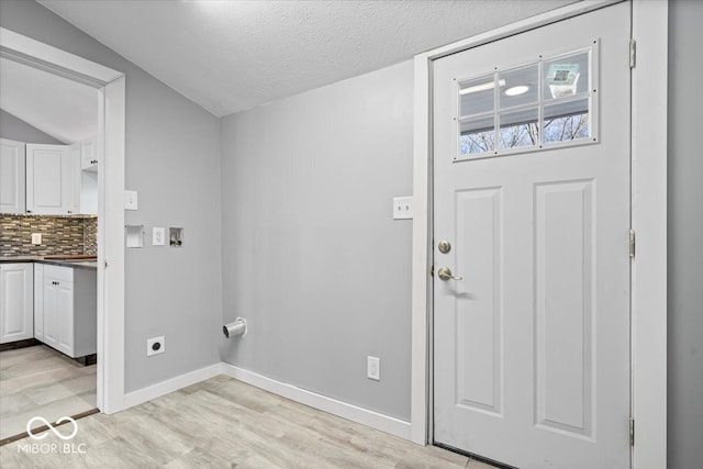 washroom featuring baseboards, laundry area, light wood-style floors, electric dryer hookup, and a textured ceiling