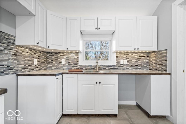 kitchen featuring decorative backsplash, white cabinetry, and a sink