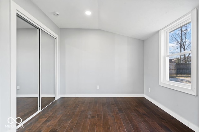 unfurnished bedroom featuring vaulted ceiling, a closet, baseboards, and wood-type flooring