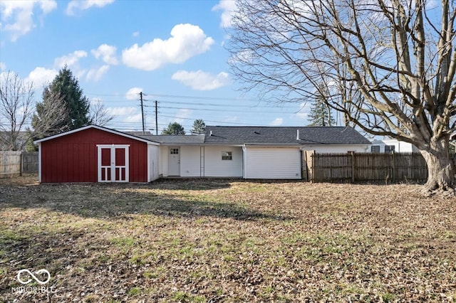 rear view of property with a storage unit, an outdoor structure, and fence