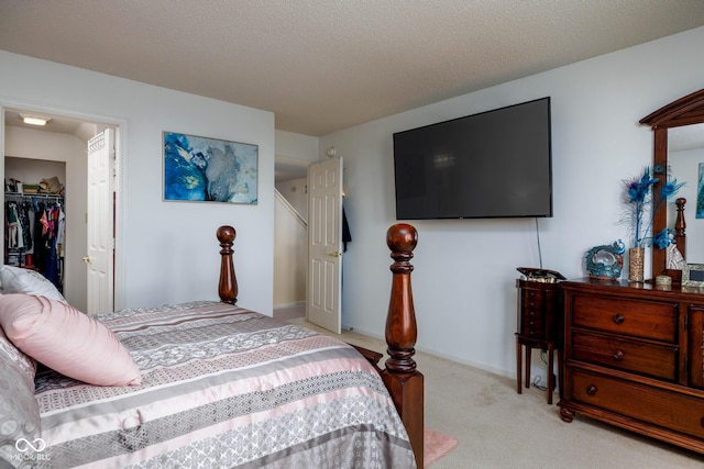 bedroom with a textured ceiling, light carpet, baseboards, a spacious closet, and a closet