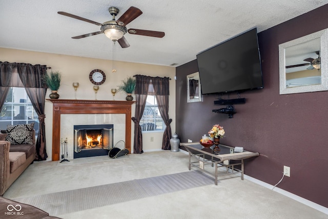 living room with carpet, a ceiling fan, a textured ceiling, a tile fireplace, and baseboards