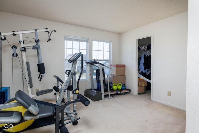 exercise area featuring a textured ceiling, carpet, and baseboards