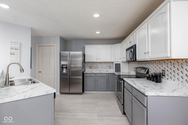 kitchen with recessed lighting, stainless steel appliances, a sink, gray cabinets, and backsplash