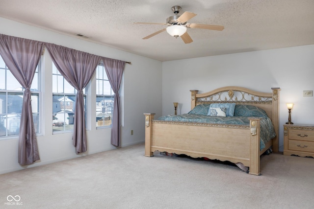 bedroom featuring light carpet, ceiling fan, a textured ceiling, and visible vents