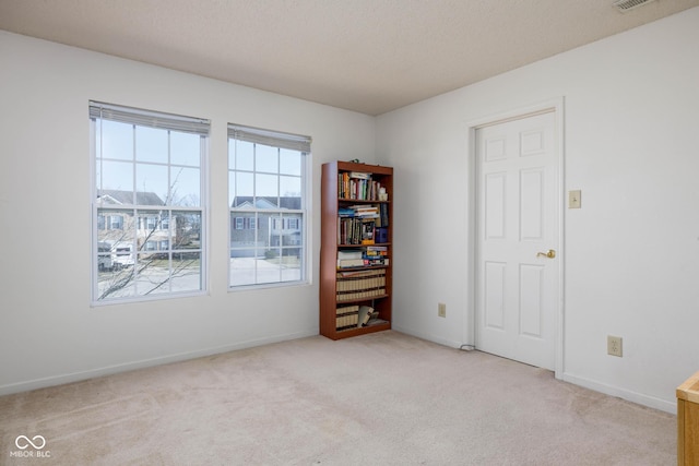 spare room with visible vents, baseboards, a textured ceiling, and light colored carpet