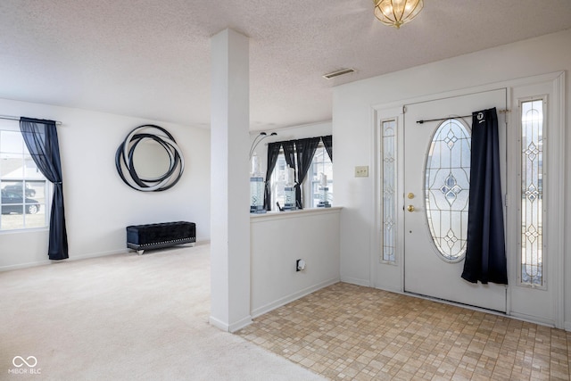 entryway featuring a textured ceiling, carpet flooring, visible vents, and baseboards