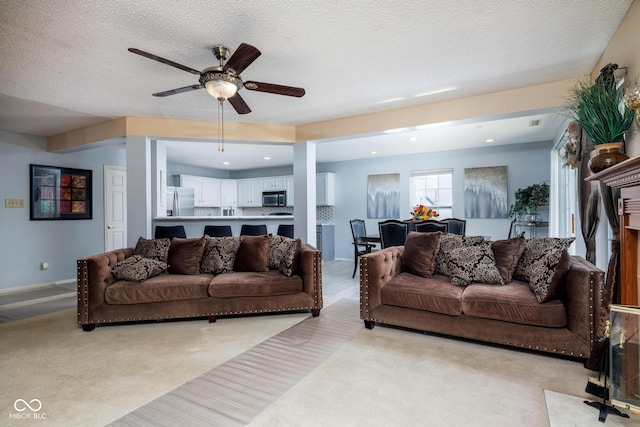 living room with a textured ceiling, ceiling fan, recessed lighting, and light colored carpet