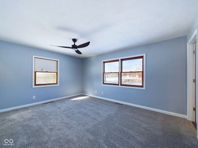 spare room featuring visible vents, baseboards, and dark colored carpet