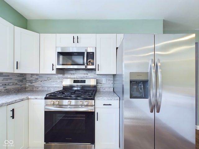 kitchen featuring light stone counters, appliances with stainless steel finishes, white cabinetry, and tasteful backsplash