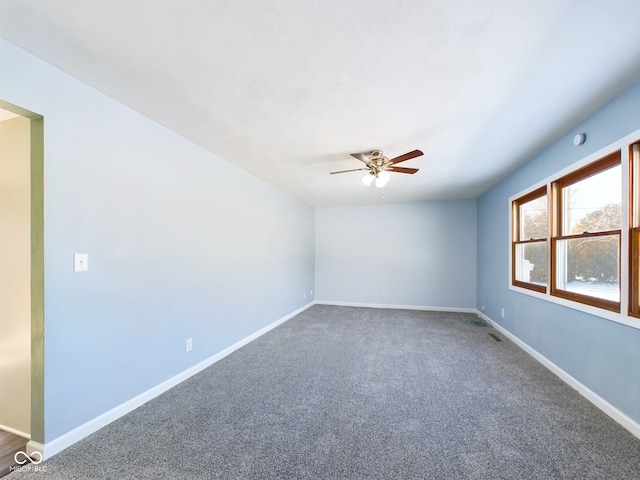 unfurnished room featuring ceiling fan, dark colored carpet, and baseboards