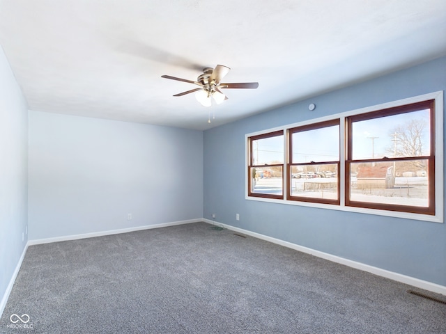 carpeted empty room featuring ceiling fan, visible vents, and baseboards