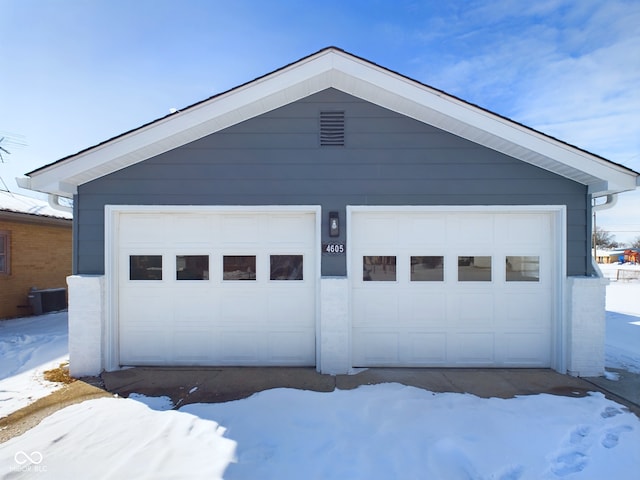 snow covered garage featuring central AC and a detached garage