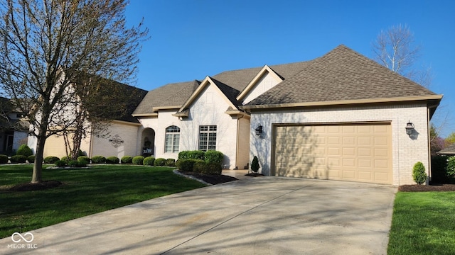1655 Rosebud Ln, Greenwood, IN 46143 - french country home featuring brick siding, a garage, concrete driveway, a front yard, and roof with shingles