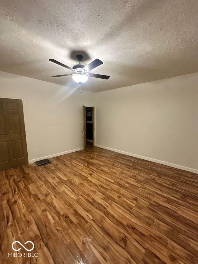 empty room with baseboards, a textured ceiling, visible vents, and wood finished floors