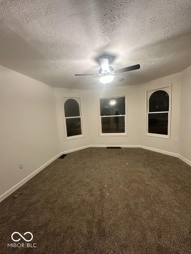 carpeted spare room with visible vents, ceiling fan, a textured ceiling, and baseboards