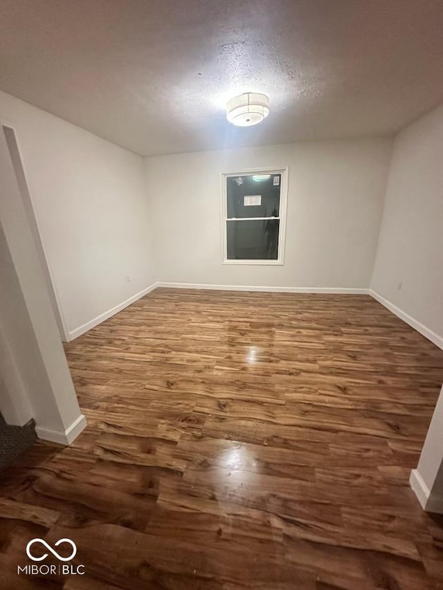 spare room with baseboards and dark wood-style flooring