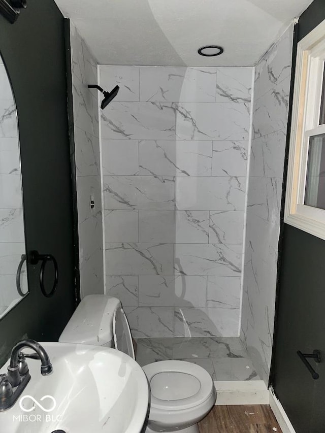 bathroom featuring wood finished floors, a sink, toilet, and a shower stall