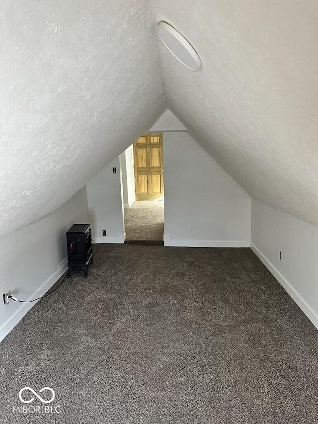 bonus room featuring lofted ceiling, baseboards, dark carpet, and a textured ceiling