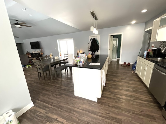 kitchen featuring dark wood finished floors, a sink, dishwasher, white cabinetry, and dark countertops