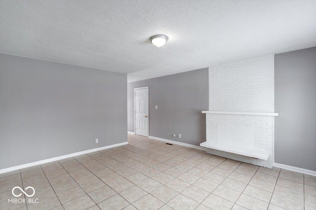 empty room featuring light tile patterned floors, baseboards, and a textured ceiling