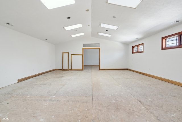 empty room featuring lofted ceiling with skylight, visible vents, and baseboards