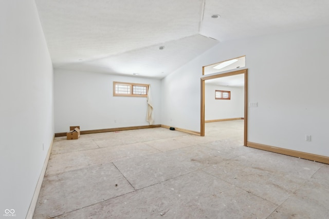 empty room with baseboards and lofted ceiling