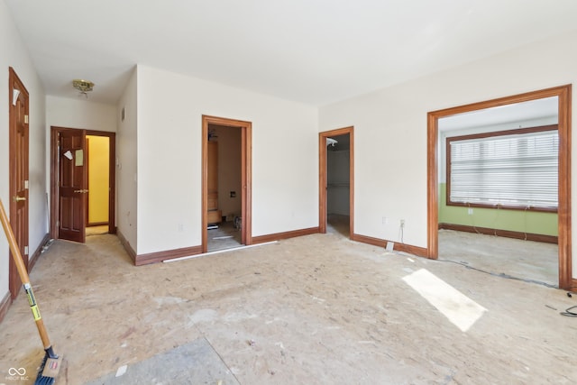 unfurnished bedroom featuring a spacious closet, a closet, and baseboards