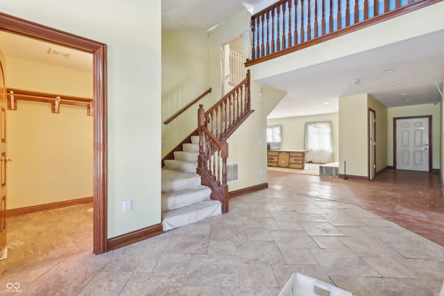 interior space featuring stone finish flooring, baseboards, visible vents, and stairs