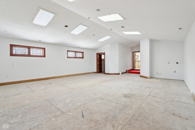 empty room with vaulted ceiling, visible vents, and baseboards