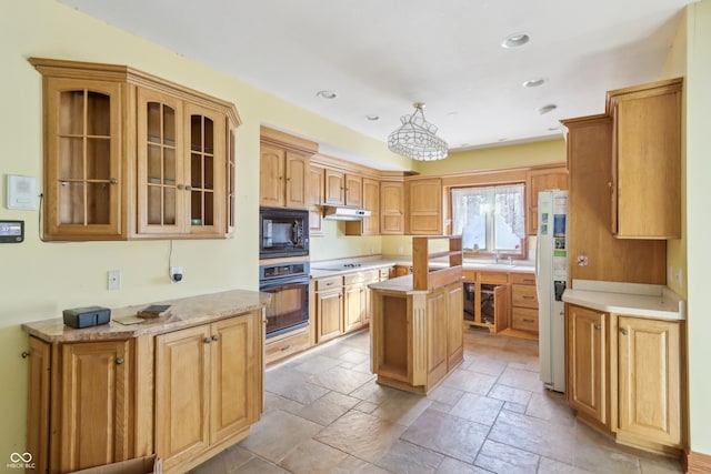 kitchen with black appliances, a sink, stone tile floors, recessed lighting, and glass insert cabinets