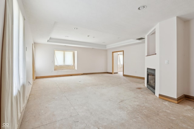 unfurnished living room with a glass covered fireplace, a raised ceiling, baseboards, and visible vents