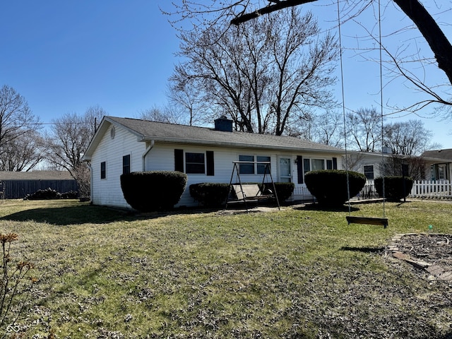 back of property with a chimney, a yard, and fence