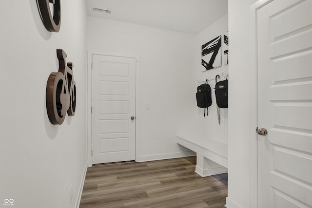 mudroom featuring baseboards, visible vents, and wood finished floors