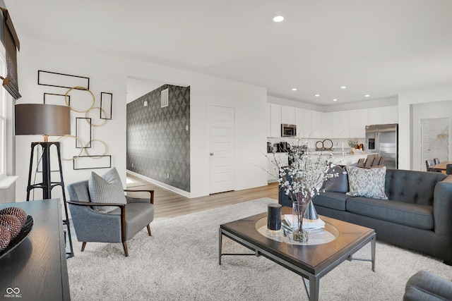 living area featuring baseboards, light wood-style flooring, and recessed lighting