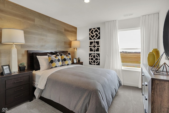 bedroom featuring baseboards, wooden walls, visible vents, and light colored carpet