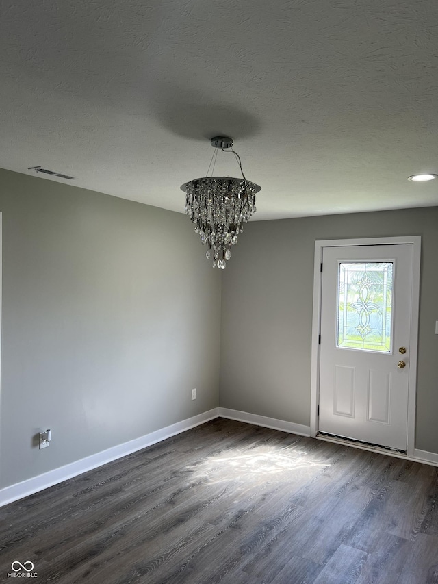 foyer with baseboards, visible vents, a chandelier, and dark wood-type flooring