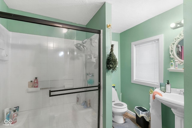 full bath with a textured ceiling, toilet, and a shower stall