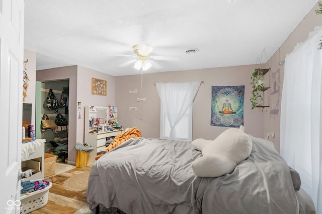 bedroom with light wood finished floors, a ceiling fan, and visible vents