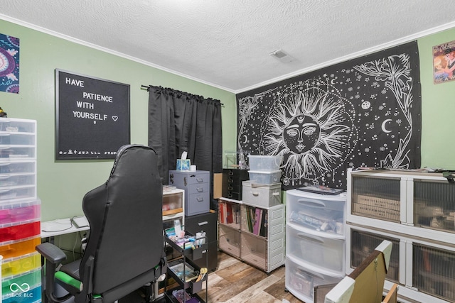 office space featuring ornamental molding, visible vents, light wood finished floors, and a textured ceiling