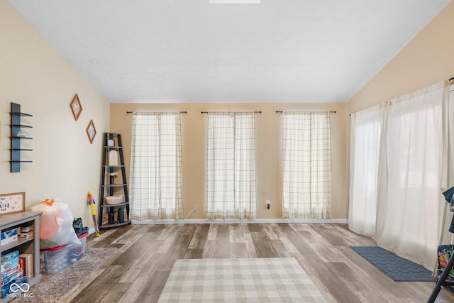 interior space with light wood-type flooring, lofted ceiling, and baseboards