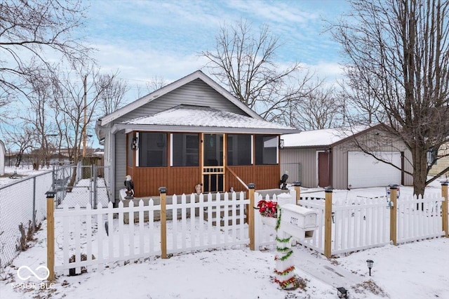 bungalow-style house featuring a garage, an outdoor structure, and a fenced front yard