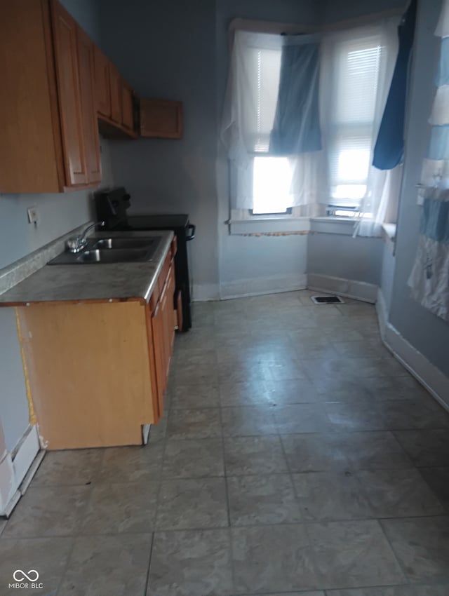 1808 E Washington St, Indianapolis, IN 46201 - kitchen featuring black / electric stove, brown cabinets, dark countertops, a sink, and baseboards