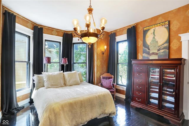 bedroom featuring a chandelier, multiple windows, and baseboards